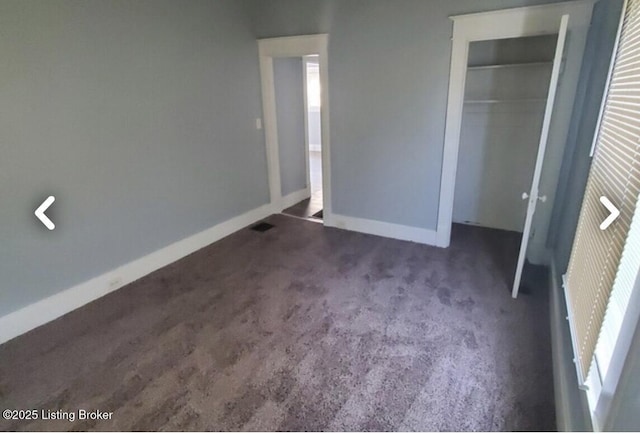 unfurnished bedroom featuring dark carpet and a closet