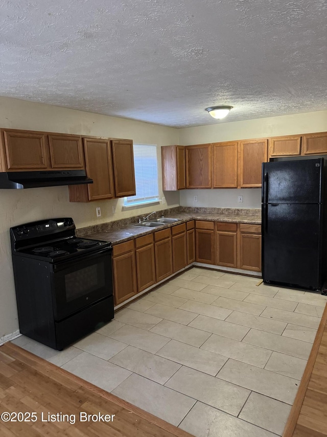 kitchen featuring sink, a textured ceiling, light wood-type flooring, and black appliances