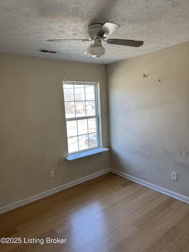 empty room with hardwood / wood-style flooring, ceiling fan, and a textured ceiling