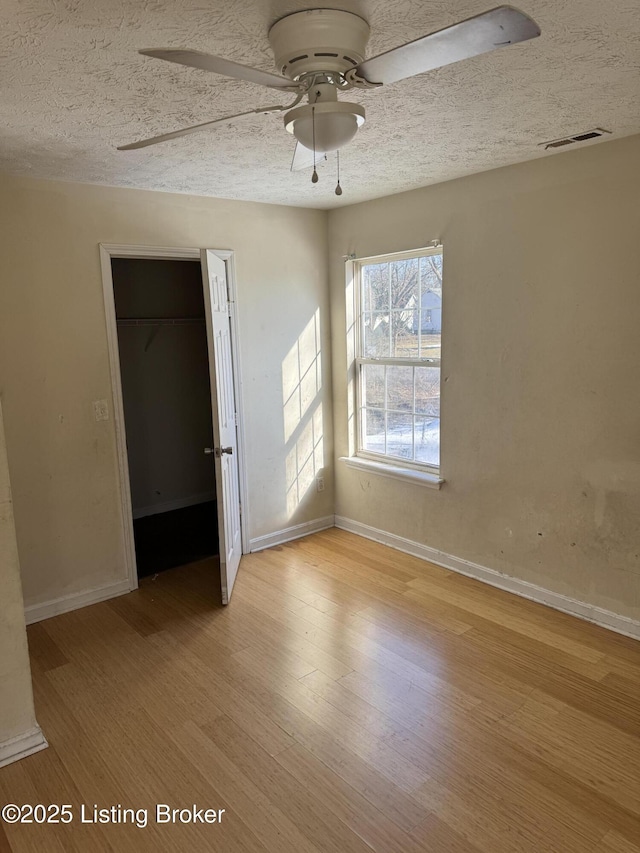 unfurnished room featuring ceiling fan, a textured ceiling, and light hardwood / wood-style floors