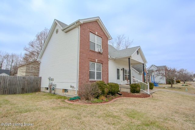 view of side of property featuring covered porch and a lawn