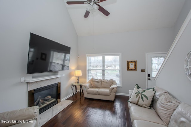 living room featuring high vaulted ceiling, a healthy amount of sunlight, hardwood / wood-style floors, and a tile fireplace