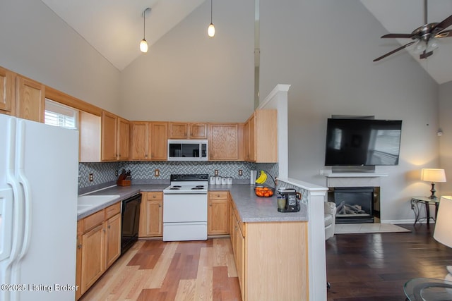 kitchen with white appliances, decorative light fixtures, light brown cabinetry, and light hardwood / wood-style floors