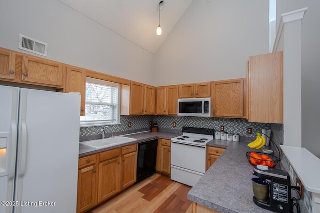 kitchen with high vaulted ceiling, decorative light fixtures, sink, white appliances, and light wood-type flooring