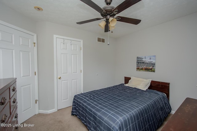 bedroom featuring light carpet, a textured ceiling, and ceiling fan