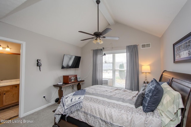 bedroom featuring ceiling fan, ensuite bath, light carpet, and vaulted ceiling with beams