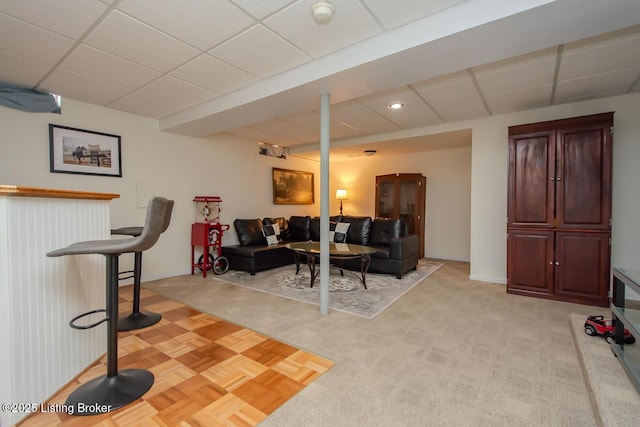 living room with a paneled ceiling and light colored carpet