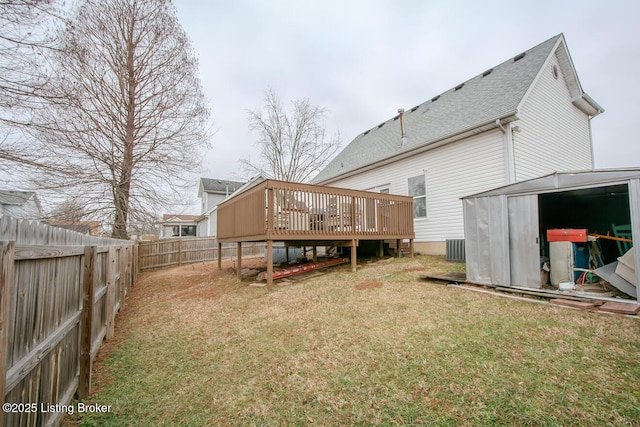 back of property featuring a yard, a deck, and a shed