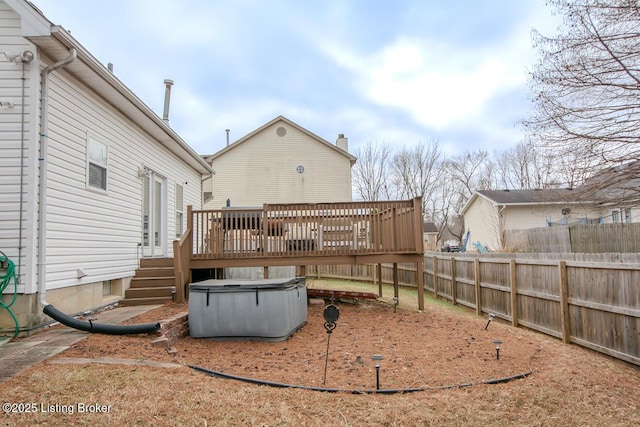 rear view of house with a hot tub and a deck