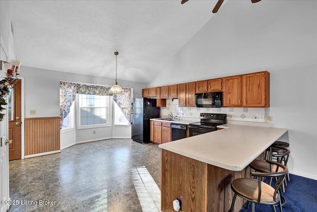 kitchen with decorative light fixtures, black appliances, sink, ceiling fan, and kitchen peninsula