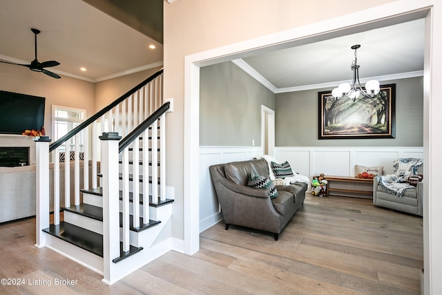 interior space with ceiling fan with notable chandelier, wood-type flooring, and ornamental molding