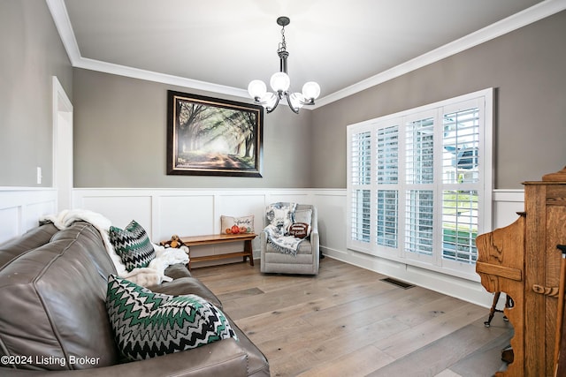 sitting room featuring hardwood / wood-style flooring, ornamental molding, and a chandelier