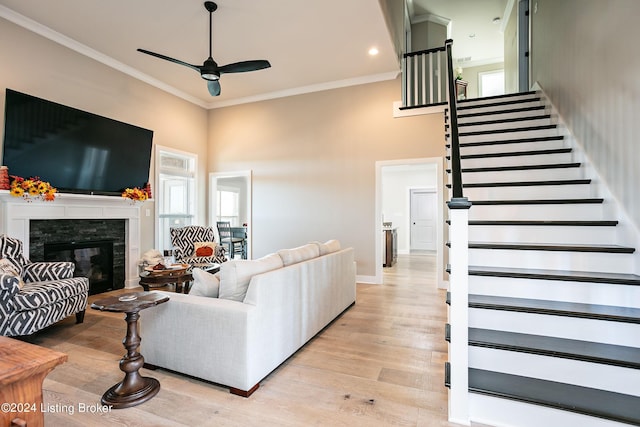 living room with ceiling fan, ornamental molding, light hardwood / wood-style flooring, and a high ceiling