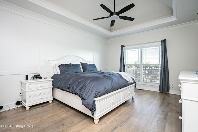 bedroom featuring a raised ceiling, crown molding, dark hardwood / wood-style floors, and ceiling fan