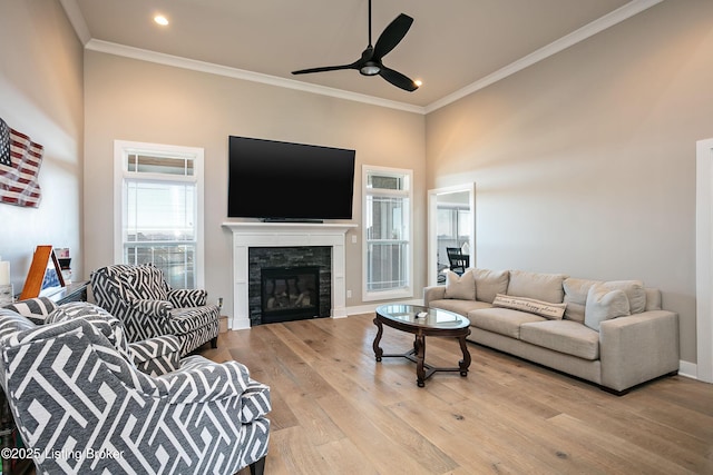 living room featuring ceiling fan, ornamental molding, hardwood / wood-style floors, and a towering ceiling