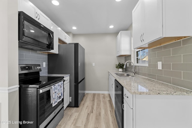 kitchen featuring sink, white cabinets, light hardwood / wood-style floors, black appliances, and light stone countertops