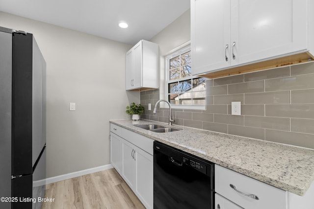 kitchen featuring sink, light stone counters, refrigerator, black dishwasher, and white cabinets