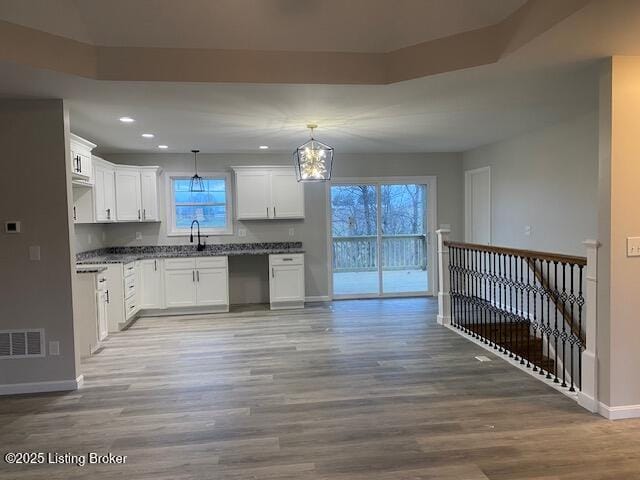 kitchen featuring decorative light fixtures, dark countertops, visible vents, white cabinetry, and light wood-type flooring