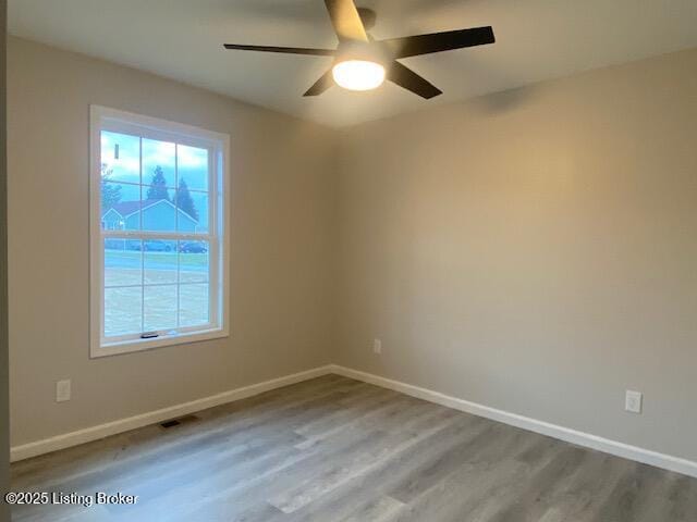 empty room featuring plenty of natural light, baseboards, and wood finished floors