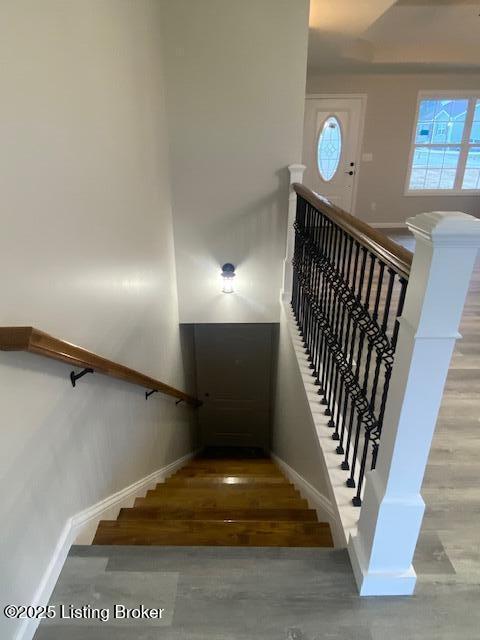 stairway featuring a towering ceiling, baseboards, and wood finished floors