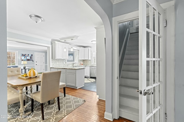 dining area featuring crown molding, sink, and light hardwood / wood-style flooring