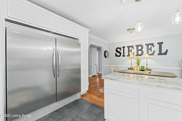 kitchen with hanging light fixtures, white cabinetry, stainless steel built in fridge, and light stone counters