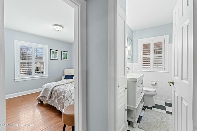 bedroom featuring ensuite bathroom and tile walls