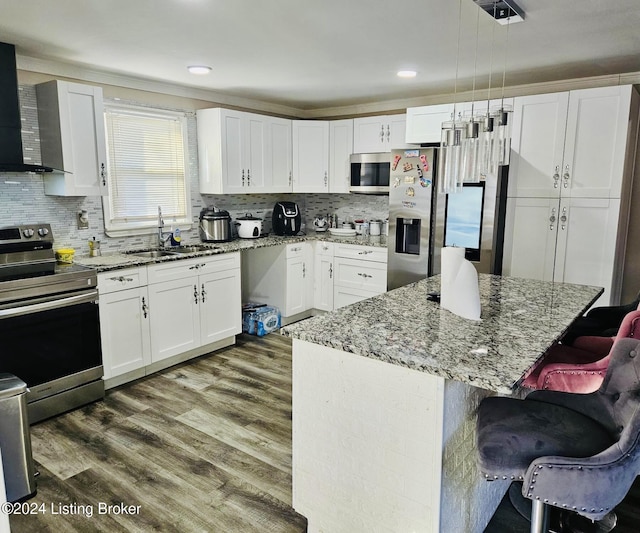 kitchen with white cabinetry, appliances with stainless steel finishes, decorative light fixtures, and a center island