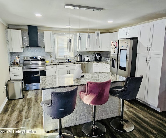 kitchen with white cabinetry, decorative light fixtures, stainless steel appliances, and wall chimney exhaust hood