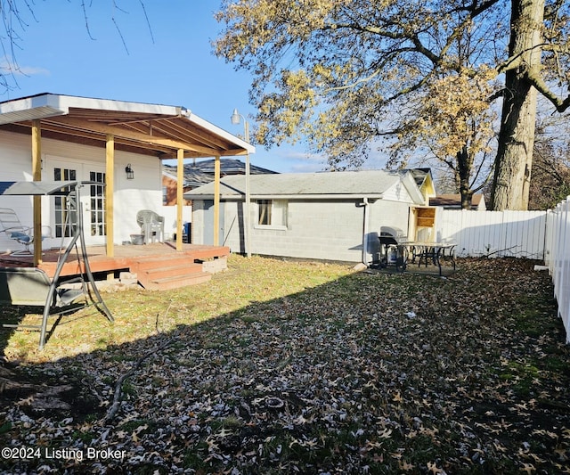 rear view of house with a wooden deck, a yard, and french doors