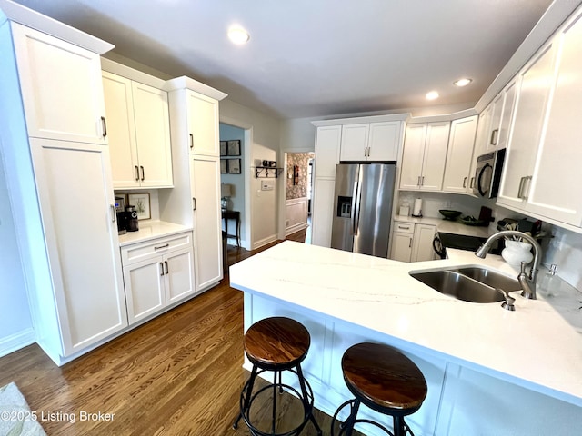 kitchen featuring sink, a breakfast bar area, stainless steel fridge, dark hardwood / wood-style flooring, and white cabinets