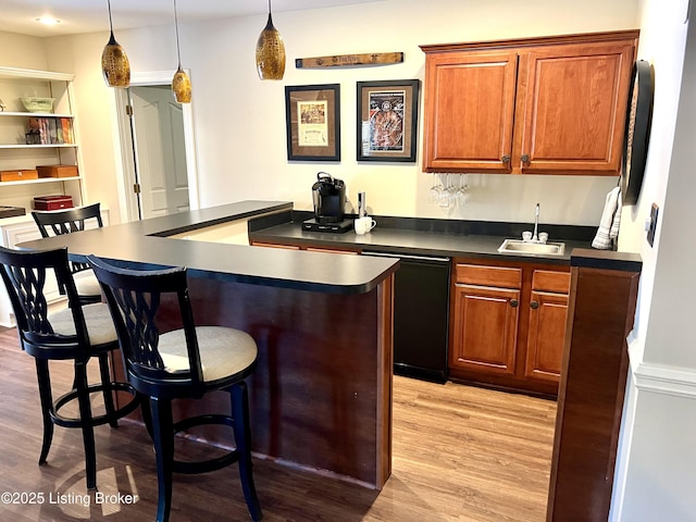 bar featuring hanging light fixtures, dishwasher, sink, and light hardwood / wood-style flooring