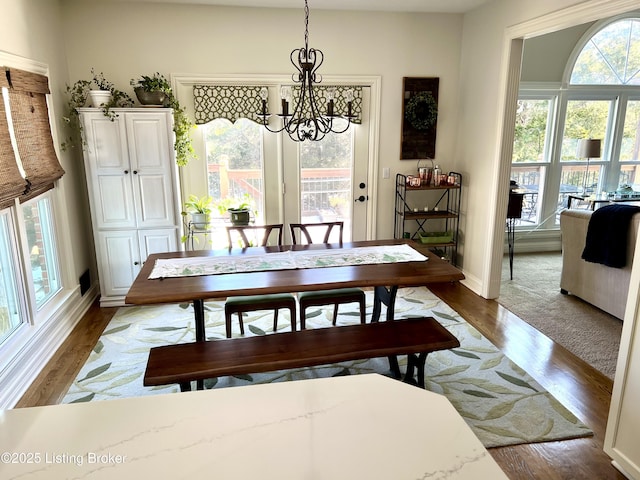 dining area with an inviting chandelier, a healthy amount of sunlight, and hardwood / wood-style floors