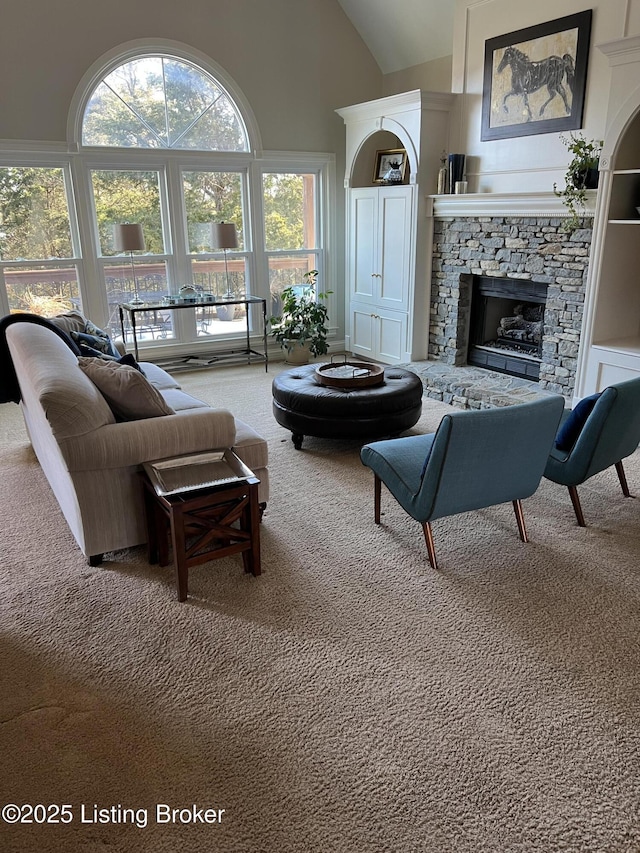 carpeted living room with a fireplace and high vaulted ceiling