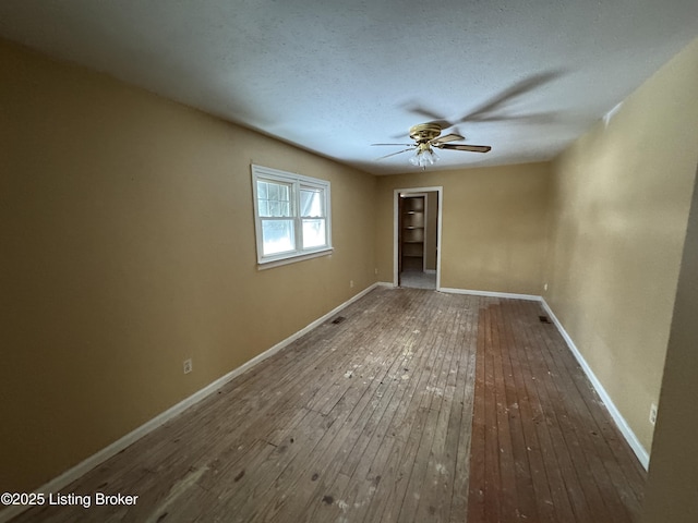 interior space featuring ceiling fan, baseboards, hardwood / wood-style floors, a closet, and a textured ceiling