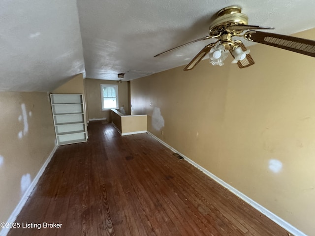 additional living space featuring lofted ceiling, a textured ceiling, hardwood / wood-style floors, baseboards, and ceiling fan