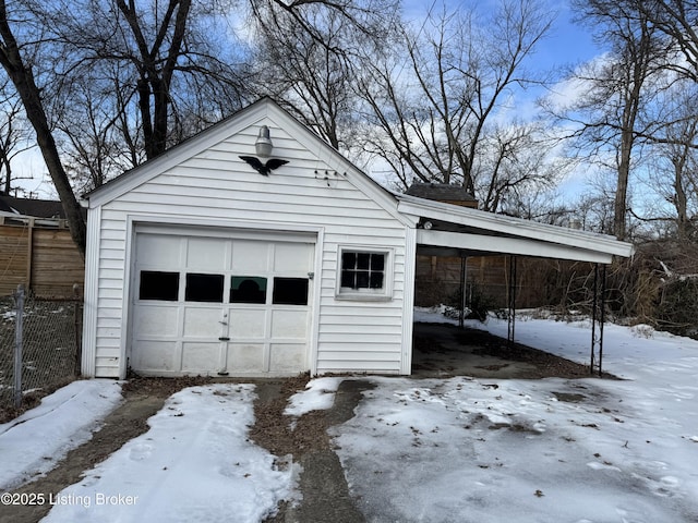 snow covered garage with a carport, fence, and a garage