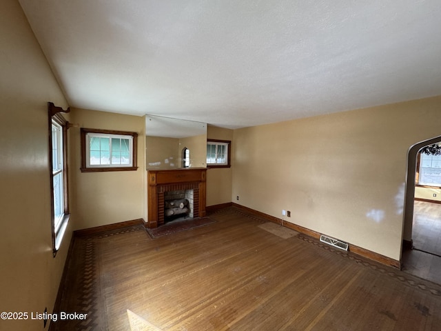 unfurnished living room with visible vents, baseboards, wood finished floors, and a fireplace