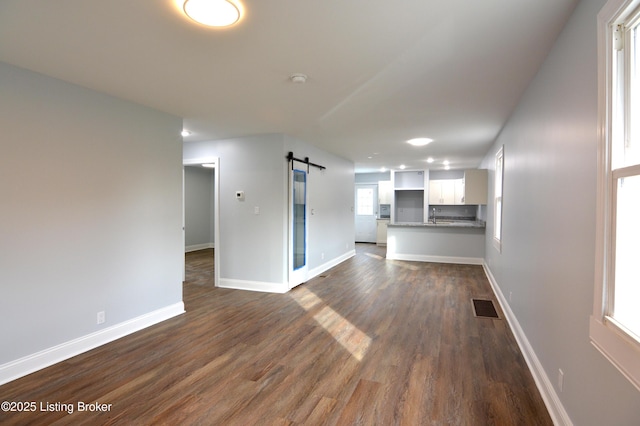 unfurnished living room with dark hardwood / wood-style floors, a barn door, and sink