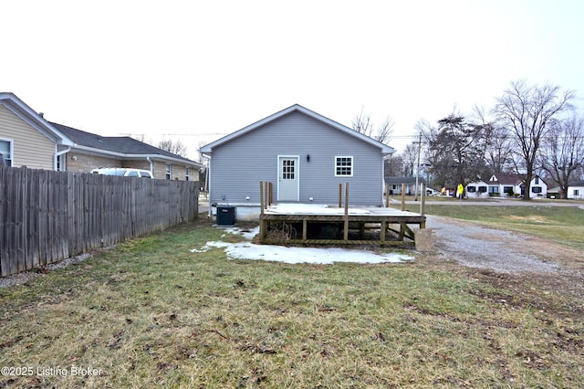 rear view of house featuring central AC unit and a lawn