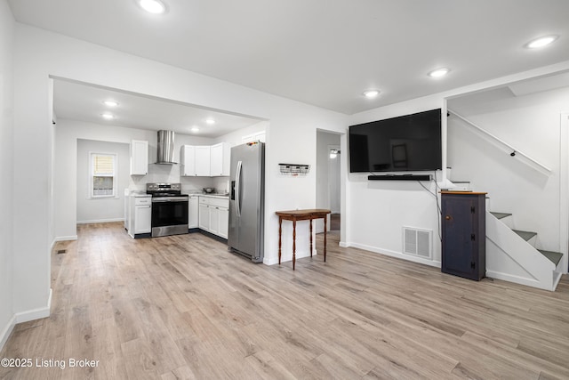 kitchen featuring white cabinetry, wall chimney range hood, light hardwood / wood-style flooring, and stainless steel appliances