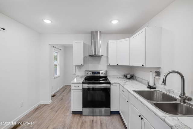 kitchen featuring white cabinetry, sink, stainless steel range with electric stovetop, light wood-type flooring, and wall chimney exhaust hood