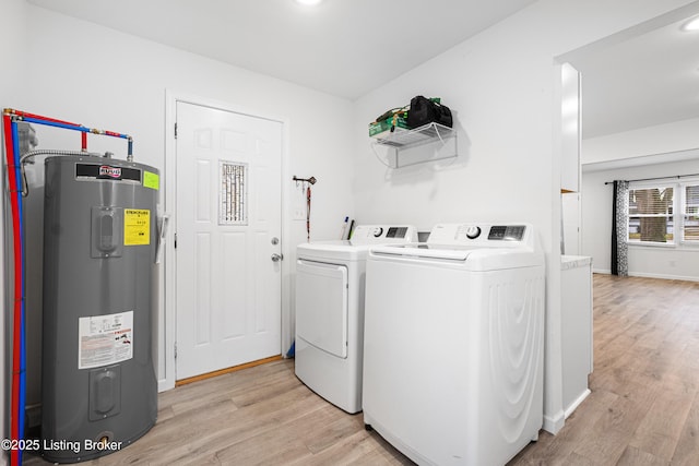 washroom with water heater, washing machine and dryer, and light wood-type flooring