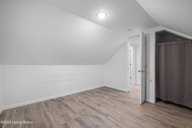 additional living space featuring lofted ceiling and light wood-type flooring