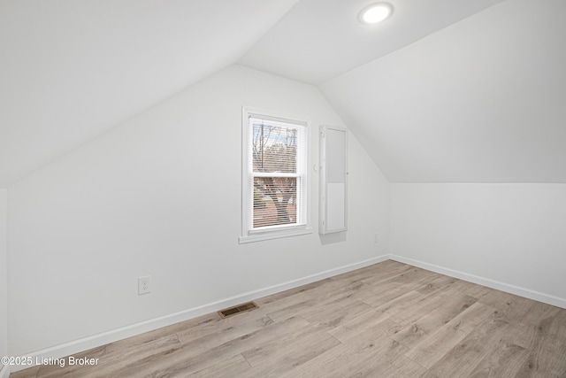 additional living space featuring vaulted ceiling and light wood-type flooring