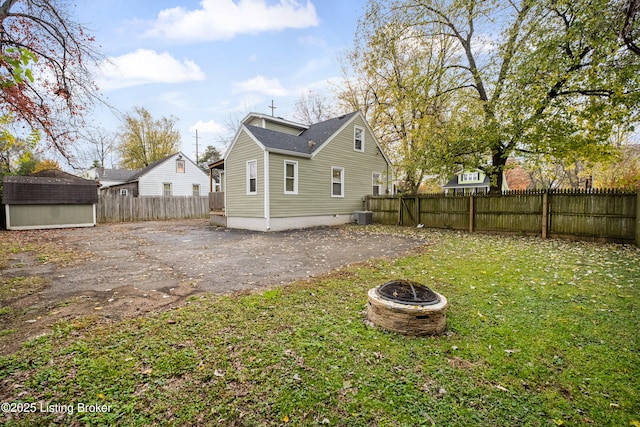 rear view of house featuring central AC unit, a fire pit, and a storage unit