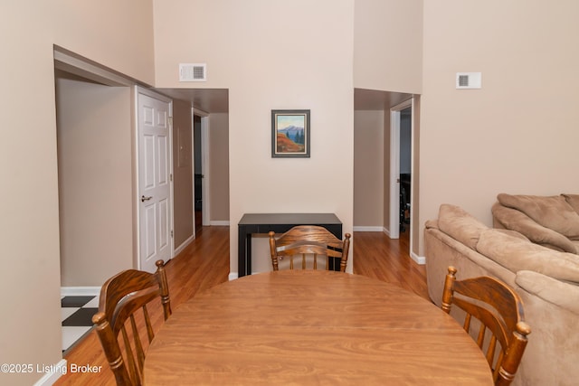 dining area with a towering ceiling and light wood-type flooring