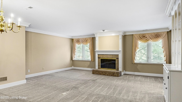 unfurnished living room with crown molding, a brick fireplace, light carpet, and an inviting chandelier