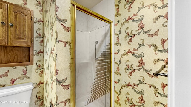 bathroom with a shower with door and toilet