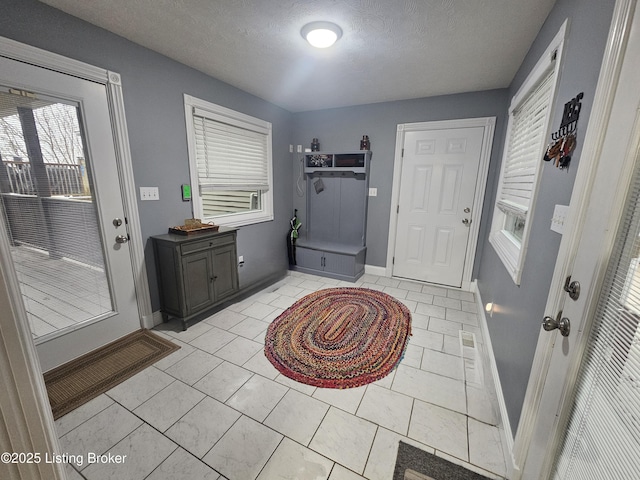 entryway with light tile patterned floors and a textured ceiling